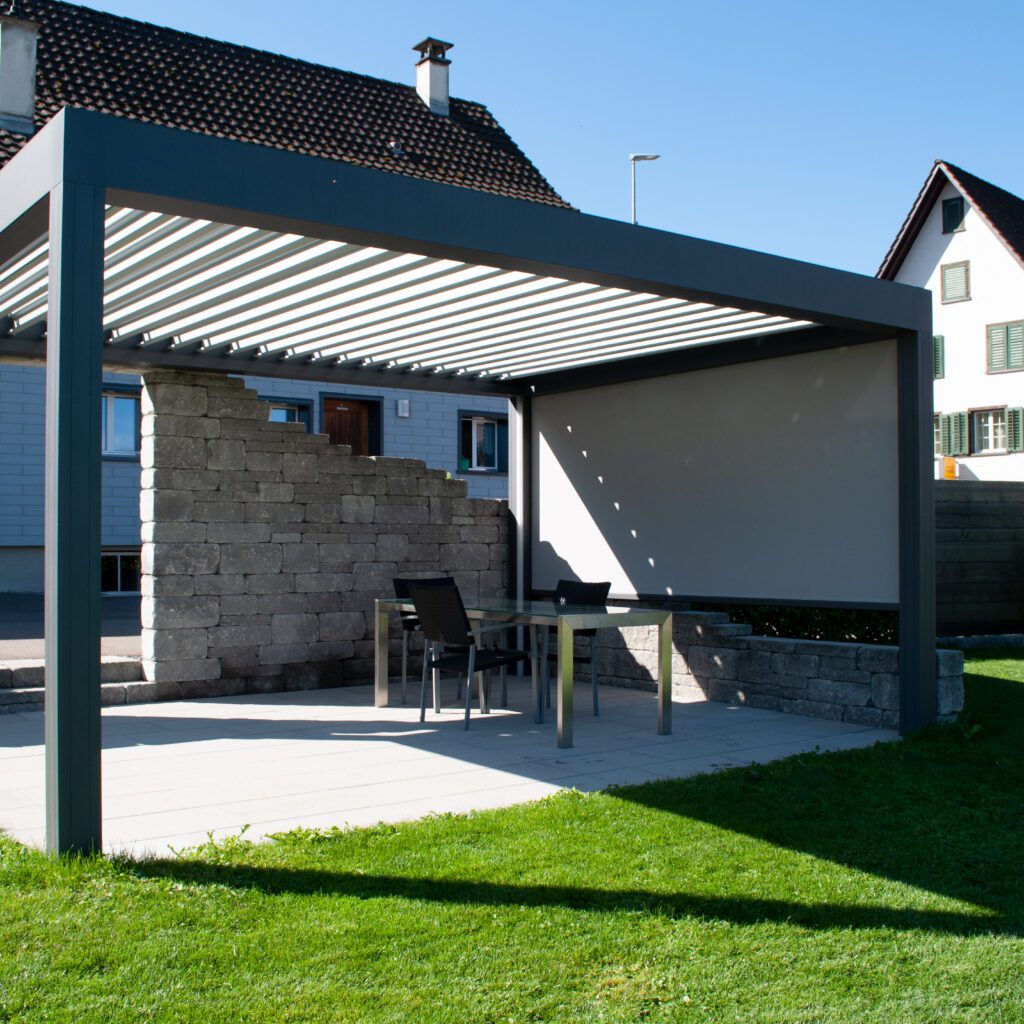 Überdachungen - Gartenueberdachung Ein Pavillon welches in einem Garten steht mit einer Steinmauer auf der einen Seite als Sicht- und Wetterschutz