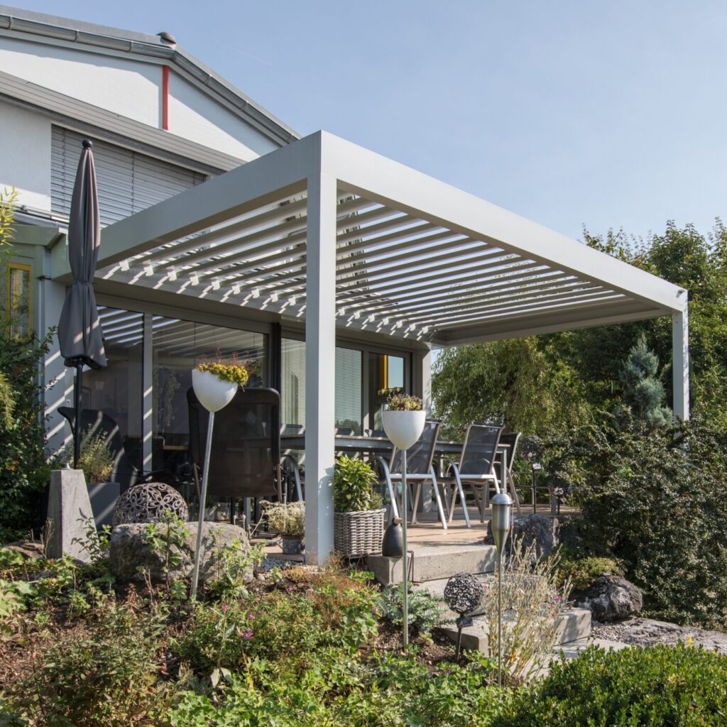 Überdachungen - Pergola System scaled e1733314586815 eine Pergola in weiss mit Wandanschluss an ein weisses Haus